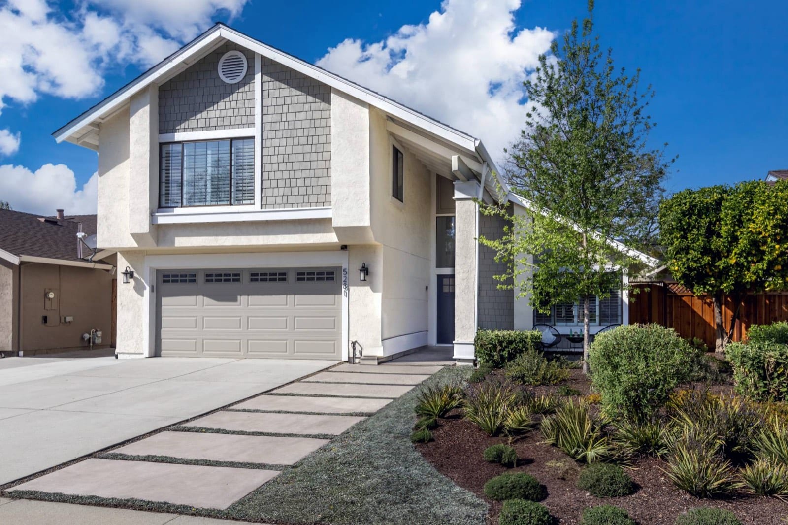Front of 5281 Rio Lobo Drive: two-story home with shingle gables, a blue front door, paver walkway and drought-tolerant landscaping