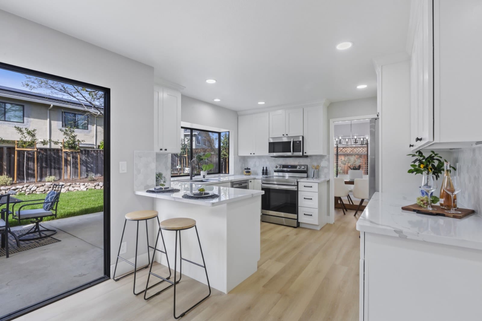 Kitchen breakfast bar with stools and the sliding door open to the patio and lawn