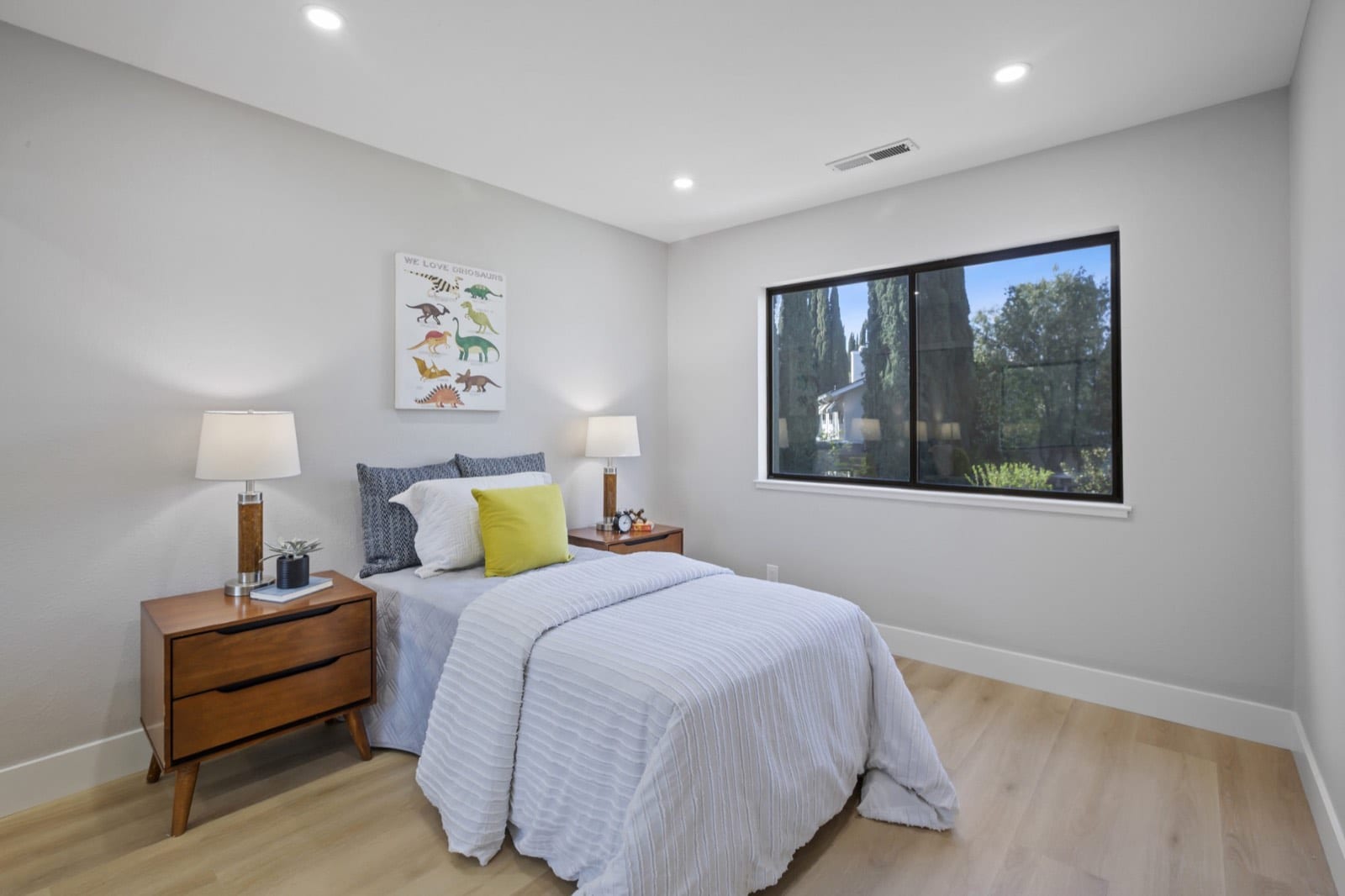 Bedroom with a twin bed, walnut nightstands and a black-framed window