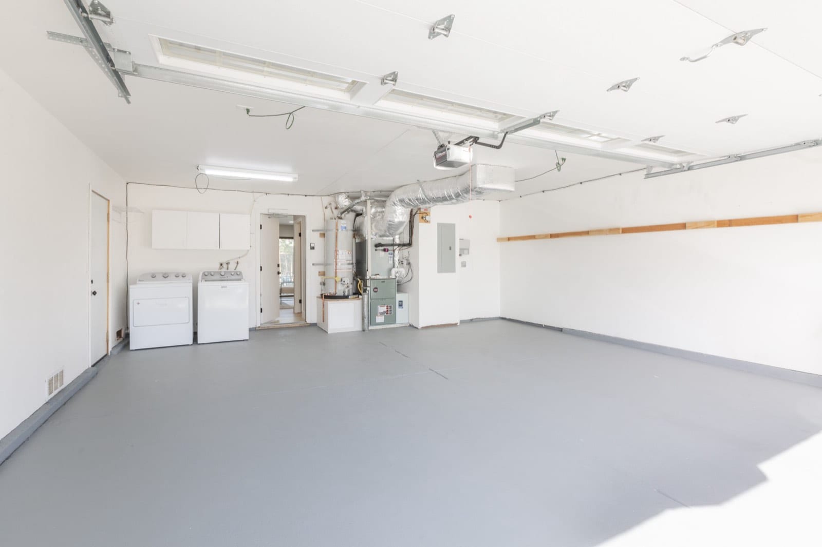 Two-car garage with a painted floor, laundry hookups and storage cabinets