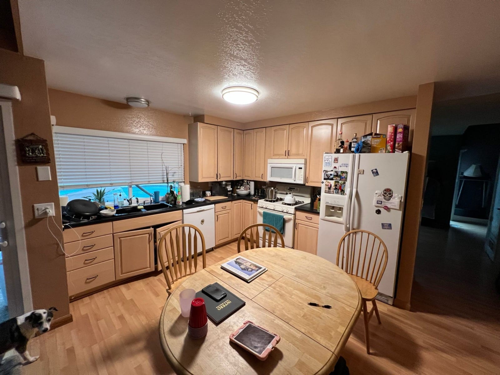 Before: kitchen with light oak cabinets, dark counters, white appliances and a round dining table