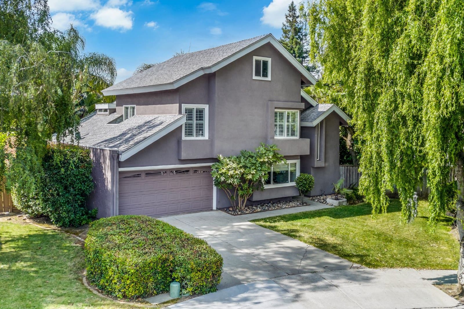 Front of 7213 Via Lomas: gray two-story home with a two-car garage, lawn and weeping willows