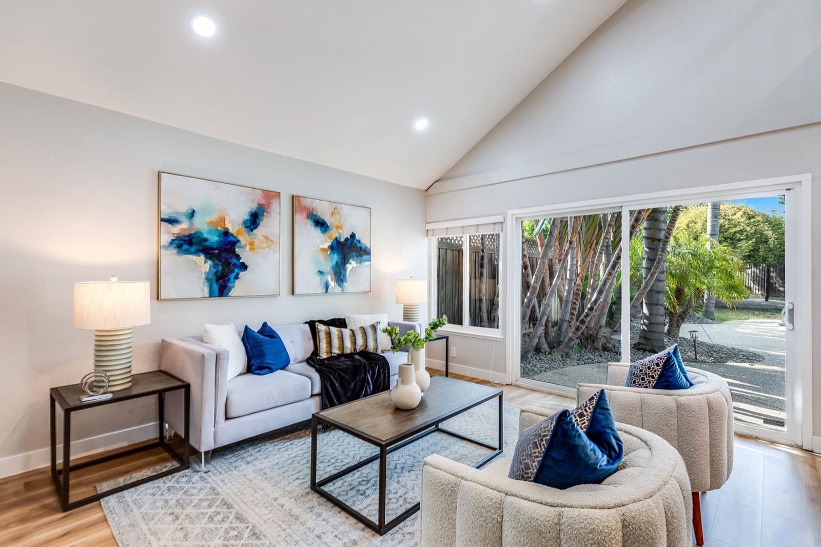 Vaulted family room with abstract art, a gray sofa and a sliding door to the side yard