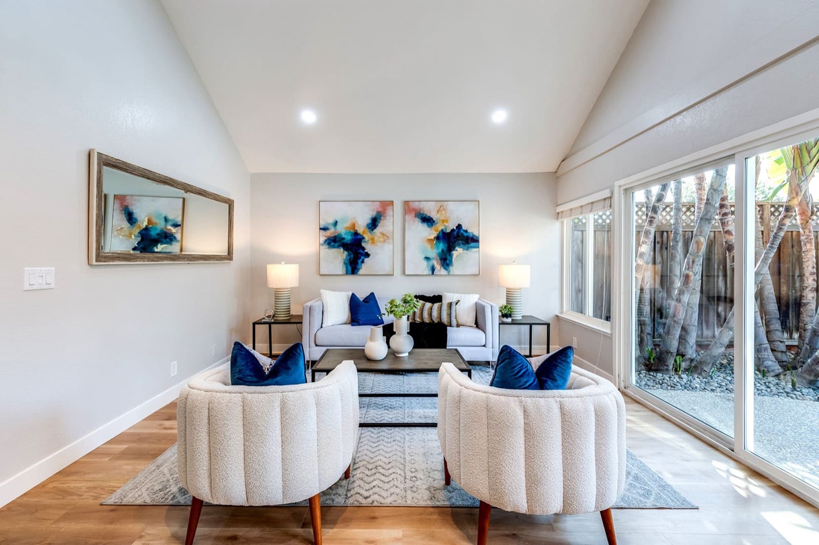 Family room seen from the entry with two boucle chairs and a wide mirror