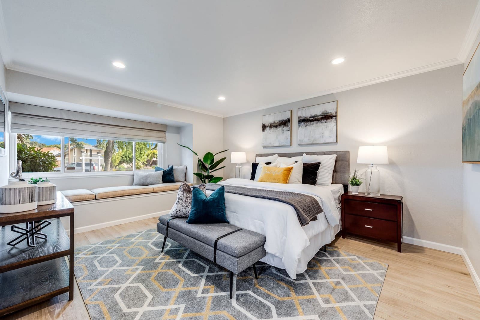Primary bedroom with a window seat, king bed and a geometric rug