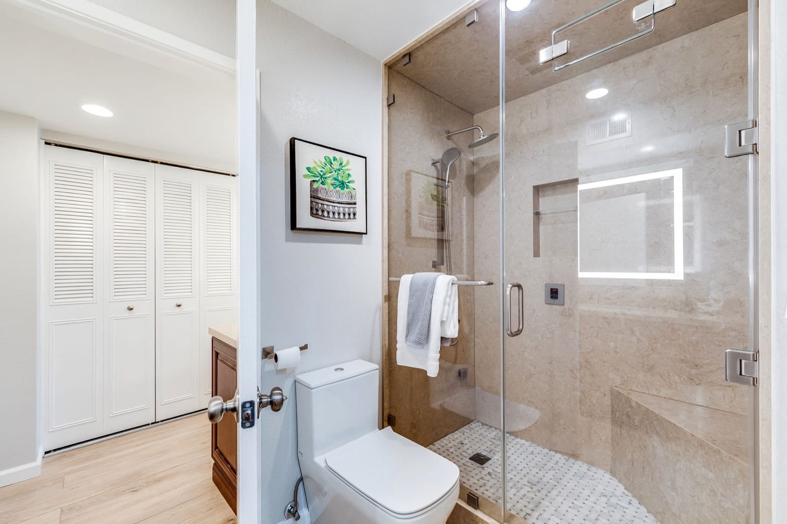 Primary bath with a frameless glass steam shower, bench and rain head