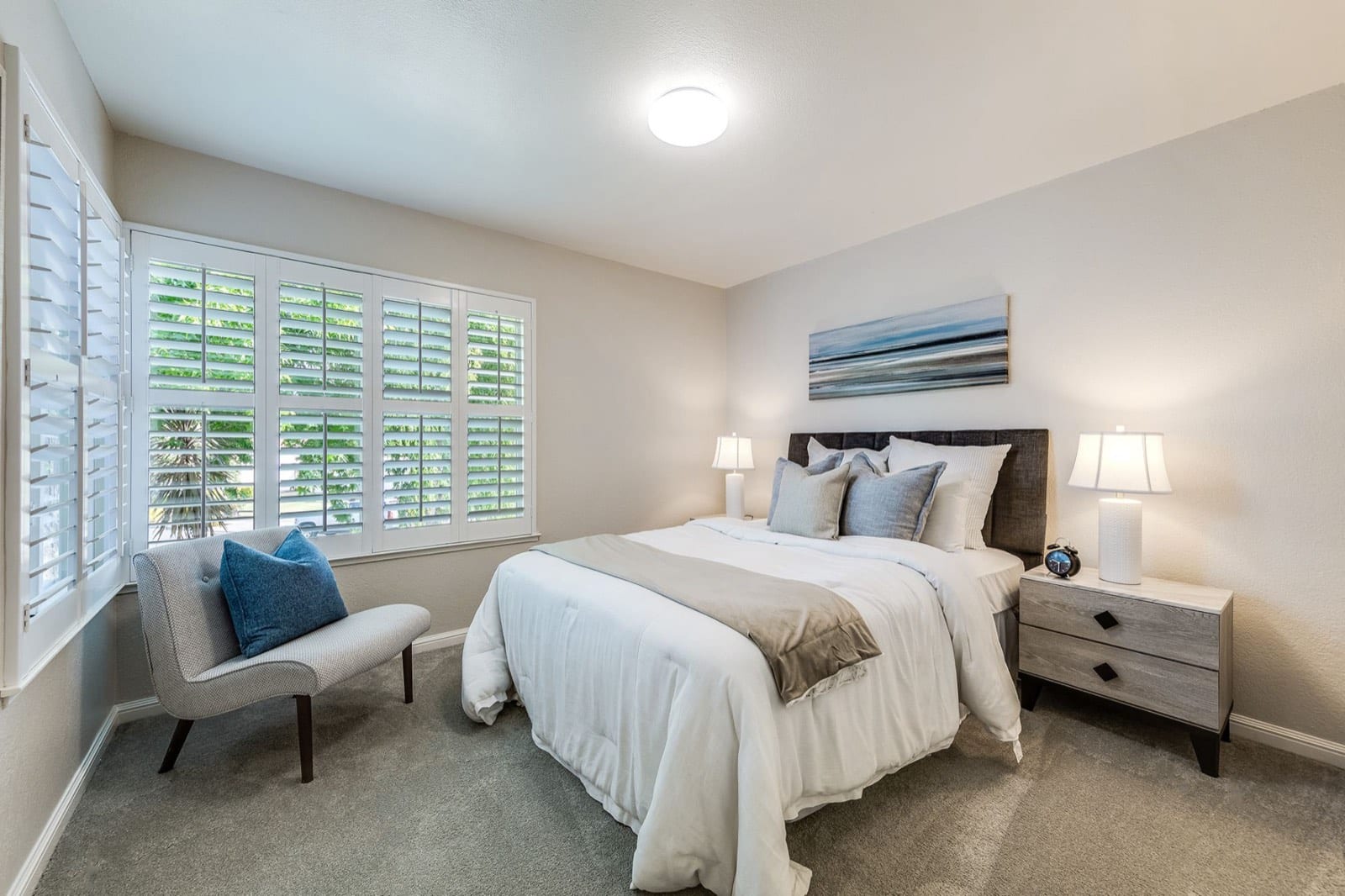 Guest bedroom with plantation shutters, a queen bed and gray carpet